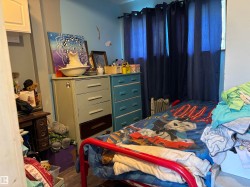 Bedroom featuring dark wood-type flooring and radiator heating unit - 