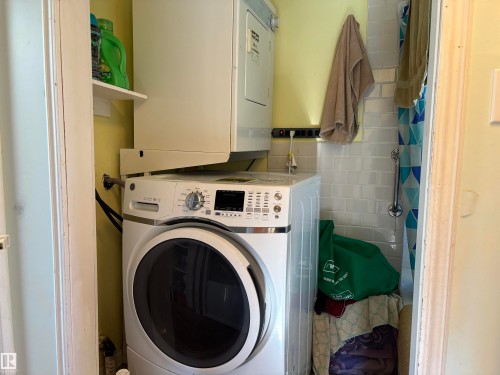 Laundry area with tile walls and stacked washer and clothes dryer - 140 Russel Drive, Rural St. Paul County, AB - Indoor Photo Showing Laundry Room
