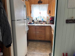 Kitchen with freestanding refrigerator, light countertops, brown cabinets, and stainless steel range oven - 