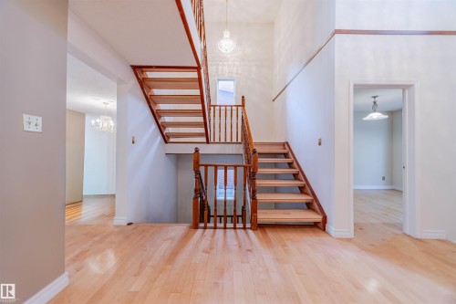 Stairs featuring a chandelier, a towering ceiling, and wood finished floors - 1602 106 Street, Edmonton, AB - Indoor Photo Showing Other Room