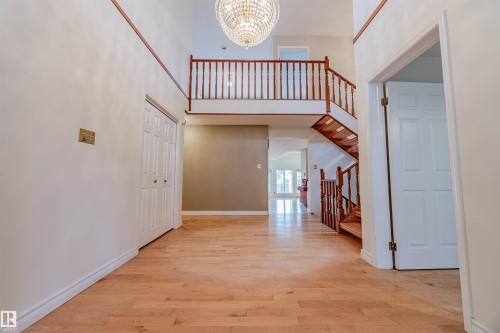 Entryway featuring a towering ceiling, light wood-style floors, a chandelier, and stairs - 1602 106 Street, Edmonton, AB - Indoor Photo Showing Other Room