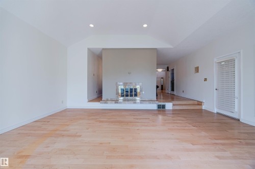 Unfurnished living room with light wood finished floors, a glass covered fireplace, recessed lighting, and lofted ceiling - 1602 106 Street, Edmonton, AB - Indoor Photo Showing Other Room