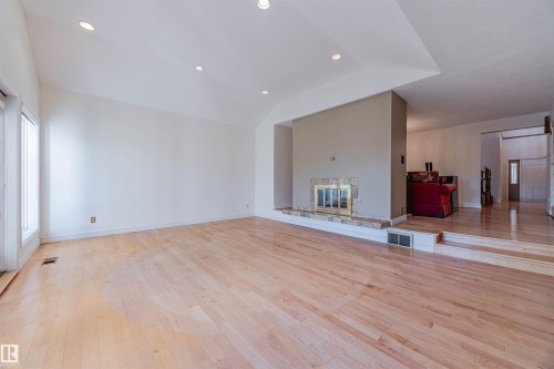 Unfurnished living room featuring light wood-style flooring, a glass covered fireplace, recessed lighting, and vaulted ceiling - 1602 106 Street, Edmonton, AB - Indoor Photo Showing Other Room
