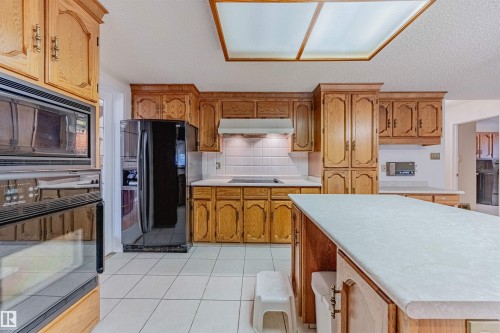 Kitchen with black appliances, tasteful backsplash, light countertops, light tile patterned flooring, and a textured ceiling - 1602 106 Street, Edmonton, AB - Indoor Photo Showing Kitchen