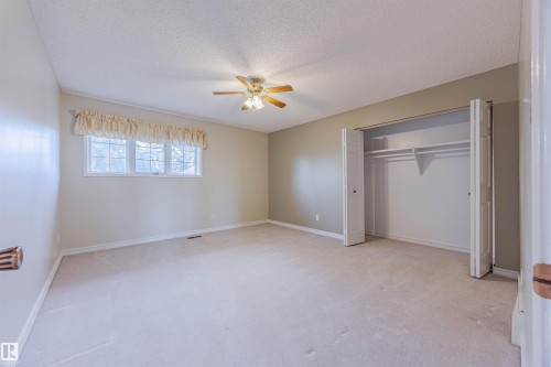 Unfurnished bedroom featuring light colored carpet, a textured ceiling, a closet, and ceiling fan - 1602 106 Street, Edmonton, AB - Indoor Photo Showing Other Room