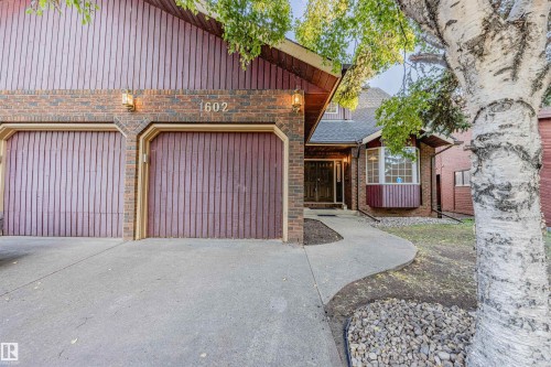View of front of home featuring concrete driveway, brick siding, roof with shingles, and an attached garage - 1602 106 Street, Edmonton, AB - Outdoor