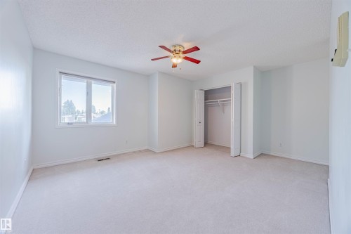 Unfurnished bedroom with light colored carpet, a ceiling fan, a closet, and a textured ceiling - 1602 106 Street, Edmonton, AB - Indoor Photo Showing Other Room