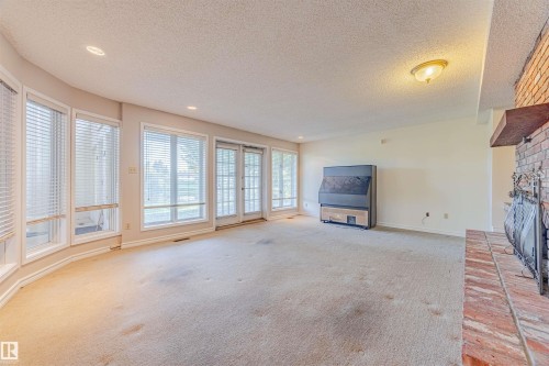 Unfurnished living room with a textured ceiling, a brick fireplace, carpet floors, and recessed lighting - 1602 106 Street, Edmonton, AB - Indoor With Fireplace