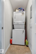 Laundry room featuring a textured ceiling, stacked washer / drying machine, and light tile patterned flooring - 