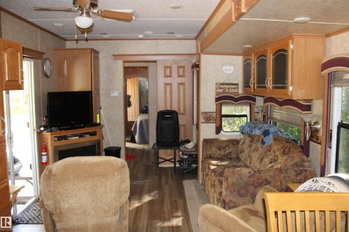 Living room with wood finished floors, ceiling fan, and crown molding - #544 12002 Twp Rd 605A, Rural St. Paul County, AB 