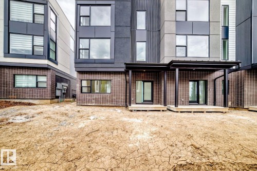 Contemporary exterior facade featuring stacked rectangular windows, dark framed glass doors, and a covered patio with black support columns - 68 5 Rondeau Drive, St. Albert, AB - Outdoor