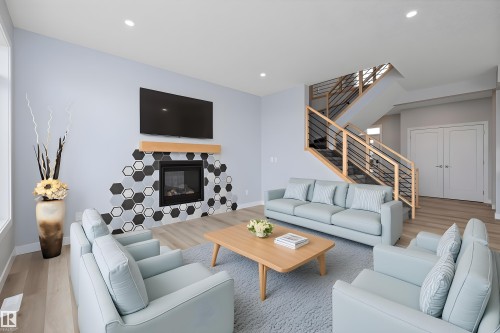 Living room featuring wood finished floors, a glass covered fireplace, stairway, and recessed lighting - 10214 92A Avenue, Morinville, AB - Indoor Photo Showing Living Room