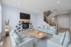 Living room featuring wood finished floors, a glass covered fireplace, stairway, and recessed lighting - 