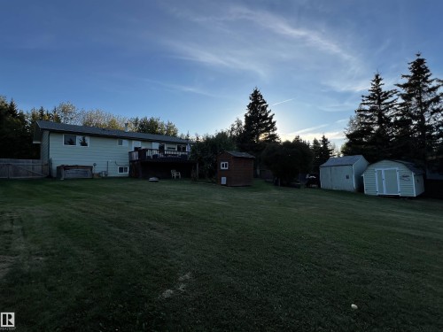 View of grassy yard with a storage unit and a wooden deck - 74038 Birch Avenue, Widewater, AB - Outdoor