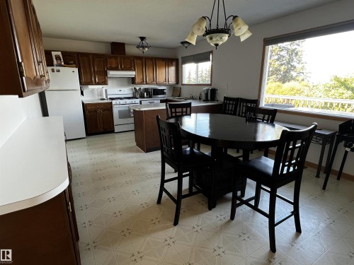 Kitchen with light floors, light countertops, white appliances, a chandelier, and dark brown cabinetry - 74038 Birch Avenue, Widewater, AB - Indoor
