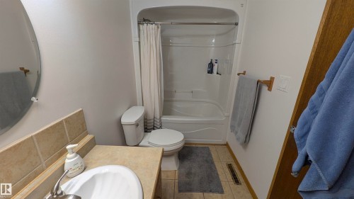 Full bathroom featuring shower / bathtub combination with curtain, light tile patterned floors, and vanity - 74038 Birch Avenue, Widewater, AB - Indoor Photo Showing Bathroom