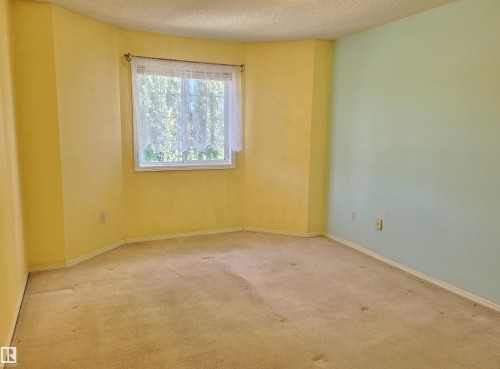Carpeted empty room with a textured ceiling and baseboards - 404 13450 114 Avenue, Edmonton, AB - Indoor Photo Showing Other Room