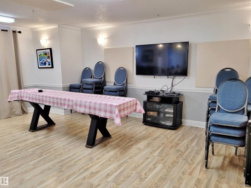 Recreation room with a textured ceiling, crown molding, and light wood-type flooring - 404 13450 114 Avenue, Edmonton, AB - Indoor