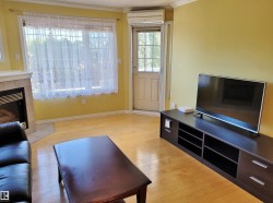 Living room, light wood finished floors, a tile fireplace, and an AC wall unit - 