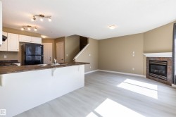 Kitchen featuring dark countertops, freestanding refrigerator, white cabinetry, a peninsula, and a kitchen breakfast bar - 