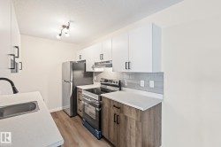 Kitchen featuring appliances with stainless steel finishes, white cabinetry, light countertops, backsplash, and a textured ceiling - 