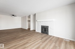 Unfurnished living room with wood finished floors, a premium fireplace, a textured ceiling, and ceiling fan - 