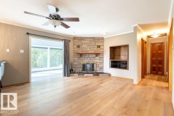 Unfurnished living room with crown molding, light wood finished floors, a fireplace, a ceiling fan, and a textured ceiling - 