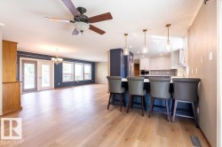 Kitchen with a kitchen bar, light wood-type flooring, tasteful backsplash, a chandelier, and blue cabinets - 