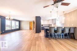 Kitchen featuring white cabinetry, a chandelier, a breakfast bar, light wood-style flooring, and crown molding - 