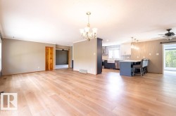 Unfurnished living room featuring ceiling fan, crown molding, a chandelier, and light wood-style flooring - 