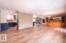 Unfurnished living room with a large fireplace, a ceiling fan, light wood-style floors, a chandelier, and ornamental molding - 