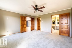 Unfurnished bedroom featuring ornamental molding, light colored carpet, connected bathroom, and a ceiling fan - 