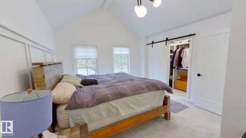 Bedroom with a barn door, beam ceiling, light carpet, high vaulted ceiling, and a walk in closet - 11308 128 Street, Edmonton, AB - Indoor Photo Showing Bedroom