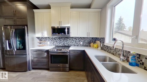 Kitchen with decorative backsplash, stainless steel appliances, light wood-style floors, dark brown cabinets, and white cabinetry - 8809 148 Street, Edmonton, AB - Indoor Photo Showing Kitchen With Double Sink With Upgraded Kitchen