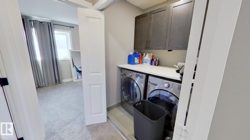 Laundry room featuring cabinet space, washing machine and clothes dryer, and light carpet - 8809 148 Street, Edmonton, AB - Indoor Photo Showing Laundry Room