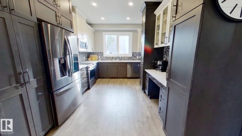 Kitchen featuring decorative backsplash, stainless steel appliances, light wood finished floors, white cabinets, and recessed lighting - 8809 148 Street, Edmonton, AB - Indoor Photo Showing Kitchen With Upgraded Kitchen