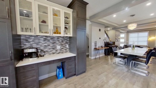 Kitchen featuring tasteful backsplash, hanging light fixtures, light wood finished floors, glass insert cabinets, and a tray ceiling - 8809 148 Street, Edmonton, AB - Indoor Photo Showing Other Room