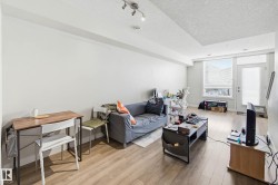 Living area with a textured ceiling, light wood finished floors, and rail lighting - 