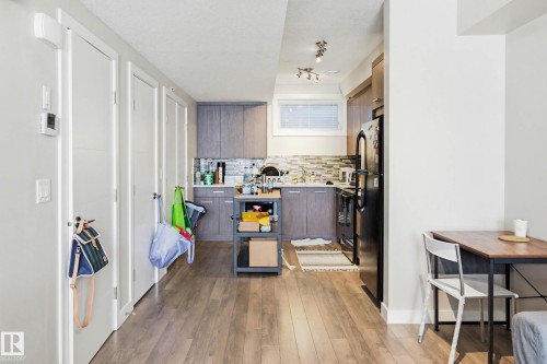 Kitchen featuring light wood-style flooring, black appliances, modern cabinets, and decorative backsplash - 90 2560 Pegasus Boulevard, Edmonton, AB - Indoor
