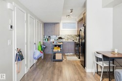 Kitchen featuring light wood-style flooring, black appliances, modern cabinets, and decorative backsplash - 