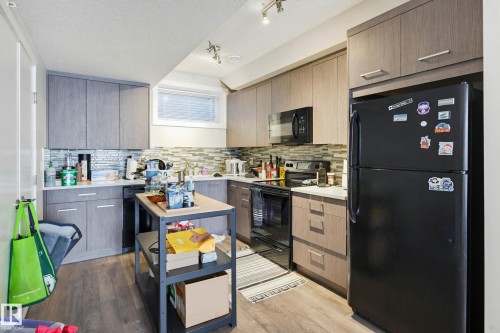Kitchen with black appliances, light countertops, modern cabinets, and a textured ceiling - 90 2560 Pegasus Boulevard, Edmonton, AB - Indoor Photo Showing Kitchen
