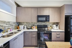 Kitchen with black appliances, modern cabinets, and light stone counters - 