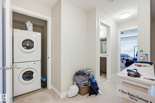 Laundry room with stacked washer and clothes dryer and light colored carpet - 90 2560 Pegasus Boulevard, Edmonton, AB - Indoor Photo Showing Laundry Room