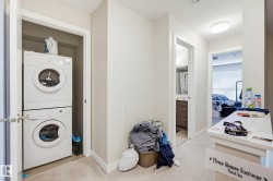 Laundry room with stacked washer and clothes dryer and light colored carpet - 