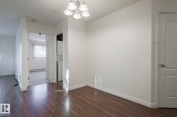 Unfurnished dining area featuring dark wood finished floors, a chandelier, stacked washing machine and dryer, and a baseboard radiator - 