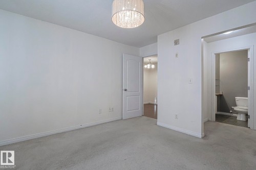 Unfurnished bedroom featuring a chandelier, carpet floors, and ensuite bath - 120 7511 171 Street Nw, Edmonton, AB - Indoor Photo Showing Other Room