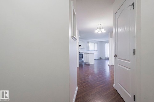Corridor with dark wood-type flooring, a chandelier, and baseboard heating - 120 7511 171 Street Nw, Edmonton, AB - Indoor Photo Showing Other Room