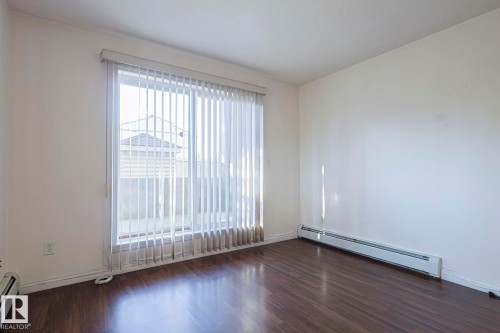 Spare room with a baseboard radiator and dark wood-style floors - 120 7511 171 Street Nw, Edmonton, AB - Indoor Photo Showing Other Room