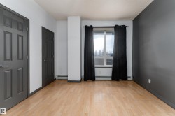 Unfurnished bedroom with light wood-style floors, a textured ceiling, multiple closets, and a baseboard radiator - 