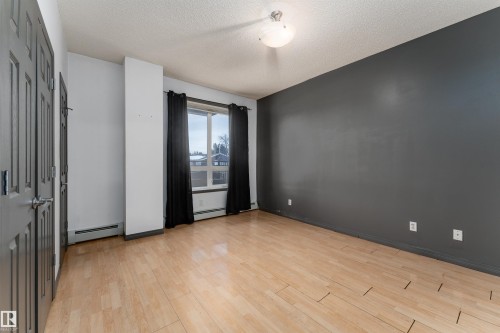 Unfurnished room with light wood-type flooring, a textured ceiling, and baseboard heating - 101 6220 134 Avenue, Edmonton, AB - Indoor Photo Showing Other Room